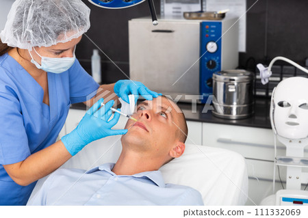 Male patient getting face tightening injections at aesthetic cosmetology clinic 111332069