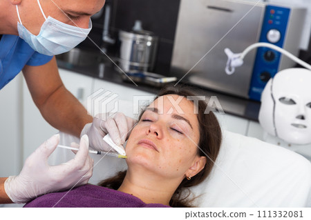 Female client during procedure of face mesotherapy in aesthetic cosmetology clinic 111332081