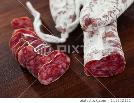 Spanish sausage fuet on a wooden table, closeup 111332132