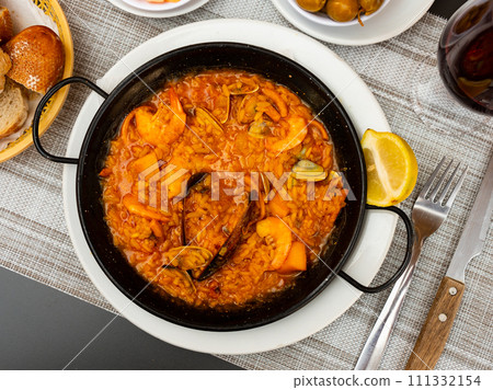 Spanish rice dish paella tinted with saffron. Prepared with olive oil and seafood 111332154