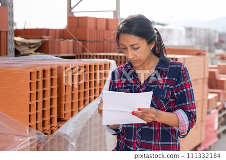 Female worker checking quantity of red bricks in warehouse Female worker checking quantity of red bricks in warehouse 111332184