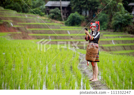 Asian Hmong Woman in Traditional Attire Using a Smartphone with copy space; The Fusion of Old and New 111332247