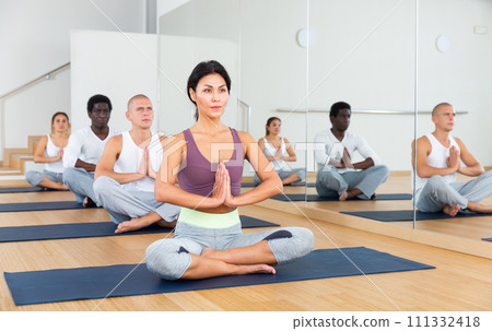 Young people meditating together at yoga class Young people meditating together at yoga class 111332418