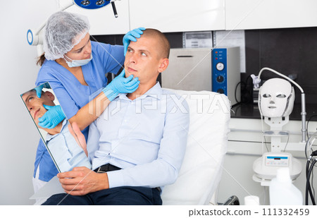 Woman beautician consulting male client before facial treatment 111332459