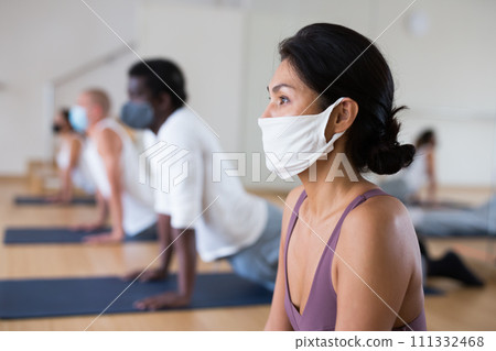 Asian woman in protective mask doing yoga with group 111332468