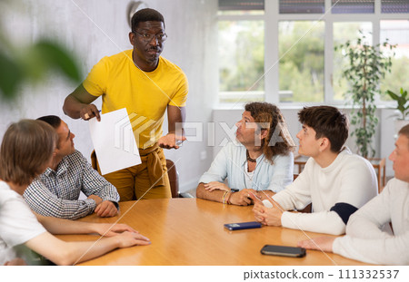 African American tutor holding paper conducting lesson for male group 111332537
