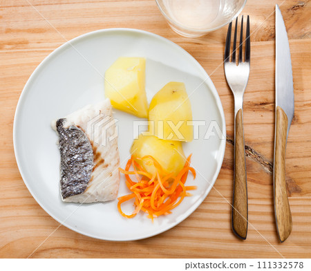 Top view of steamed hake with potatoes, grated carrot 111332578