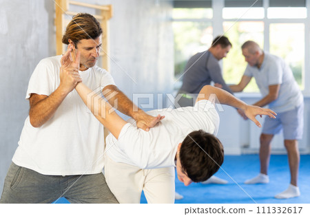 Young guy and man practice wrestling, apply techniques of Aikido and self-defense. 111332617