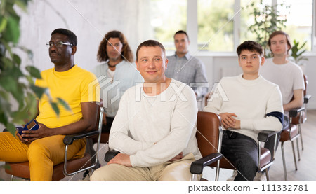Cheerful man listening to presentation with group of men Cheerful man listening to presentation with group of men 111332781
