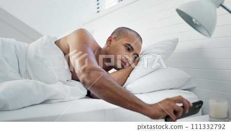 Morning, text and man on a phone in bed with social media and web scroll at home. Mobile networking, relax and bedroom with an African male person with chat notification and typing in a house 111332792