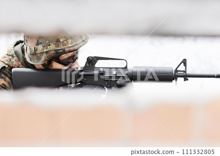 Sharp shooter. Profile of a soldier aiming a gun with a slot in the foreground. 111332805