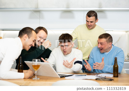 Group of football fans drinking beer and watching football match on laptop at home 111332819