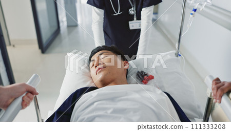 Asian man, patient and push bed in hospital for surgery, emergency or medical problem in corridor. Medicine, professional or person with stretcher for wellness, service and risk in clinic or job Asian man, patient and push bed in hospital for surgery, emergency or medical problem in corridor. Medicine, professional or person with stretcher for wellness, service and risk in clinic or job 111333208