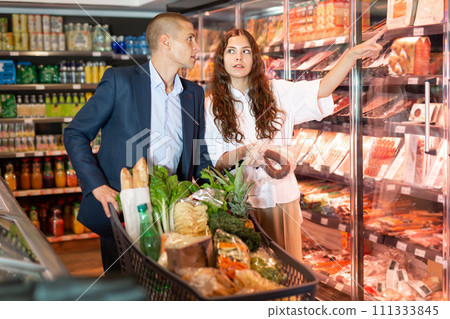 Young couple choose a sausage at the supermarket 111333845