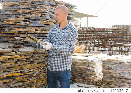 Male worker checking quantity of natural stone tiles in warehouse Male worker checking quantity of natural stone tiles in warehouse 111333847
