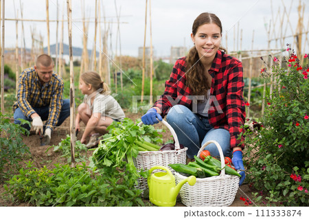 Young woman farmer posing with harvest of ripe vegetables 111333874