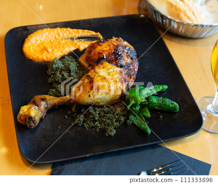 Chicken drumstick with couscous with black curry, peppers and Romesco Chicken drumstick with couscous with black curry, peppers and Romesco 111333896