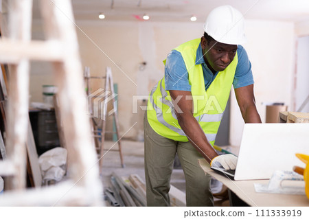 African american engineer checks a home renovation plan on a laptop African american engineer checks a home renovation plan on a laptop 111333919