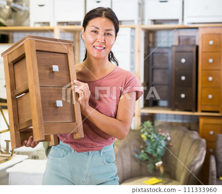 Woman in store with small cabinet in hands Woman in store with small cabinet in hands 111333960
