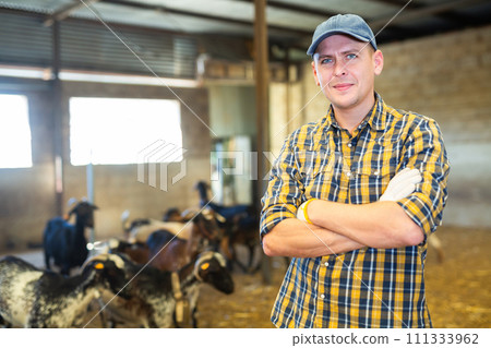 Experienced livestock farm worker standing in goat stall Experienced livestock farm worker standing in goat stall 111333962