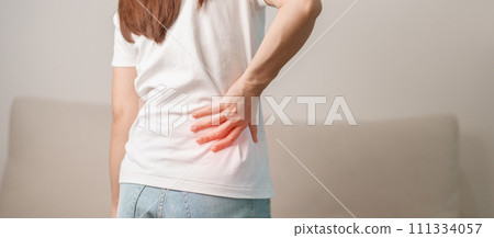woman having back body ache during sitting on Couch at home. adult female with muscle pain due to Piriformis Syndrome, Low Back Pain and Spinal Compression. Office syndrome and medical concept 111334057