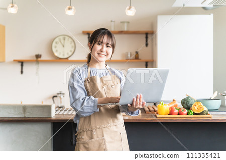Asian woman searching for recipes and nutrients using laptop in home kitchen Asian woman searching for recipes and nutrients using laptop in home kitchen 111335421