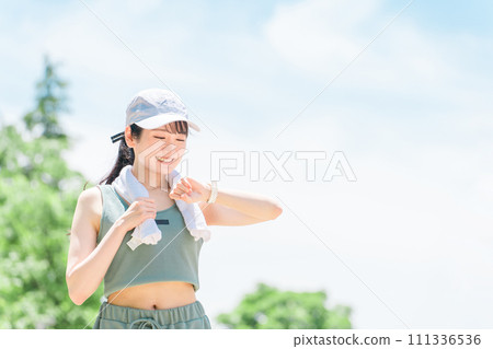 A woman exercising, training, and walking while looking at a smartwatch in the park (time, time, healthcare) A woman exercising, training, and walking while looking at a smartwatch in the park (time, time, healthcare) 111336536