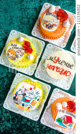 Colorful Cupcakes with Intricate Frosting Designs in Plastic Containers on Green Background Colorful Cupcakes with Intricate Frosting Designs in Plastic Containers on Green Background 111336802
