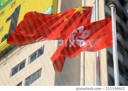 Chinese and hong kong flag set up in the event for celebrating the National Day of the People's Republic of China 74 th anniversary with the office building background via the window Chinese and hong kong flag set up in the event for celebrating the National Day of the People's Republic of China 74 th anniversary with the office building background via the window 111336922