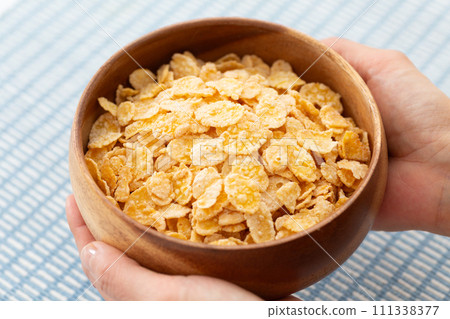 Woman's hand holding cornflake cereal Woman's hand holding cornflake cereal 111338377