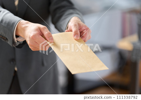 Businessman holding out an envelope 111338792