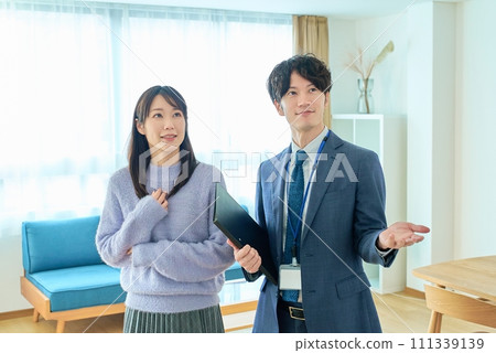 A man in a suit explaining the room to a woman A man in a suit explaining the room to a woman 111339139