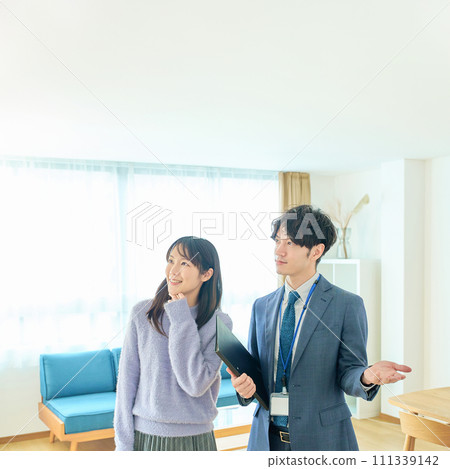 A man in a suit explaining the room to a woman A man in a suit explaining the room to a woman 111339142
