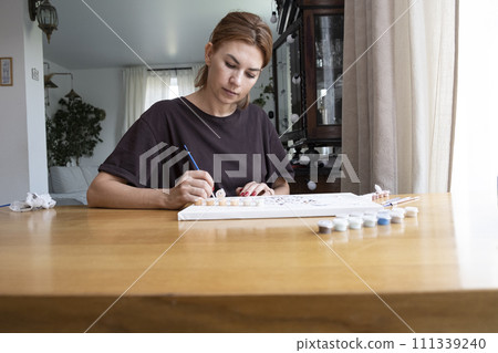 Adult woman draws a picture by numbers. Middle age person Adult woman draws a picture by numbers. Middle age person 111339240