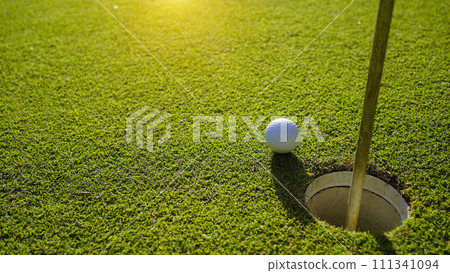 Top view of a golf ball on green course at hole. Top view of a golf ball on green course at hole. 111341094