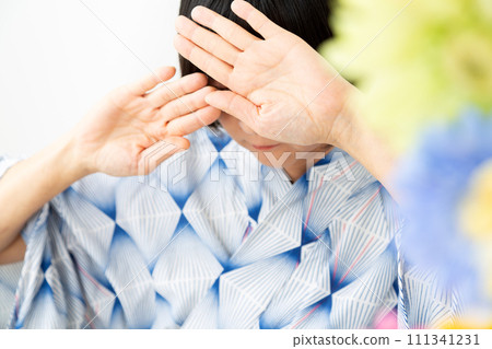 一位身穿藍色浴衣的中年婦女雙手遮擋夏日陽光 111341231