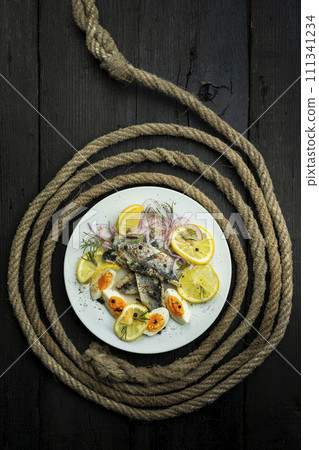 Herring fish fillets with eggs, herbs, onion and lemon on a white plate. Top view, flat lay photo 111341234