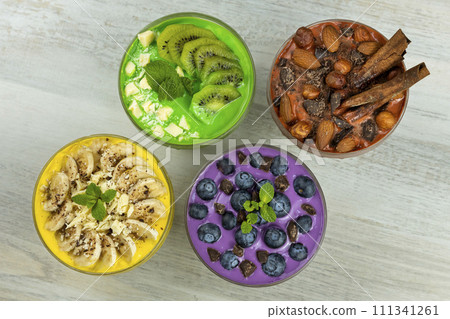 Smoothies or puddings with kiwi, bannas, blueberries and chocolate with almonds and hazelnuts in a crystal bowls.Top view image 111341261