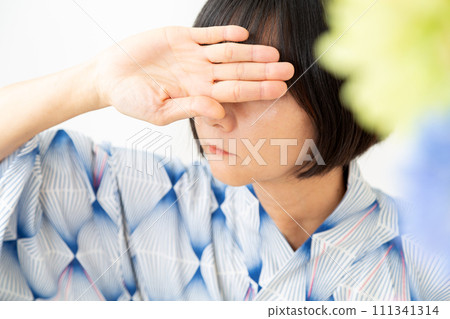 一位身穿藍色浴衣的中年婦女雙手遮擋夏日陽光 111341314