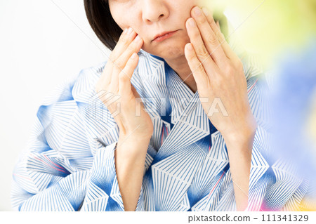 一名身穿藍色浴衣的中年婦女擔心臉上曬傷 111341329