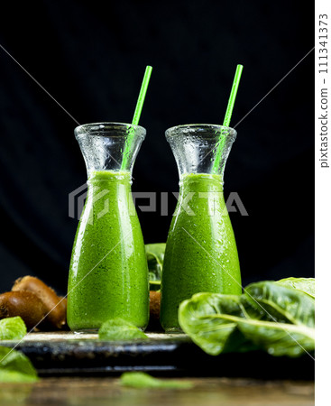 Healthy green smoothies with spinach, apple, kiwi, broccoli and mint in glass jar with fruits and vegetables on the wooden table. Detox and healthy concept 111341373