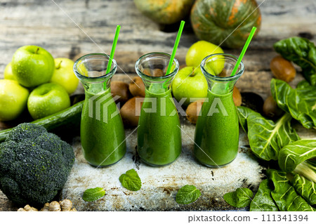 Healthy green smoothies with spinach, apple, kiwi, broccoli and mint in glass jar with fruits and vegetables on the wooden table. Detox, diet, healthy, vegetarian drink concept 111341394