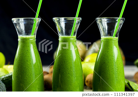 Healthy green smoothies with spinach, apple, kiwi, broccoli and mint in glass jar with fruits and vegetables on the wooden table. Detox, diet, healthy, vegetarian drink concept Healthy green smoothies with spinach, apple, kiwi, broccoli and mint in glass jar with fruits and vegetables on the wooden table. Detox, diet, healthy, vegetarian drink concept 111341397