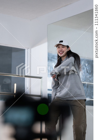 Cheerful young woman recording dance video tutorial for social media in studio 111341860