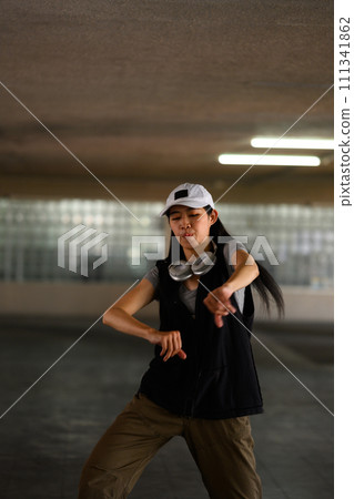 Young woman hip hop dancer dancing with passion and energy in a dark parking garage 111341862