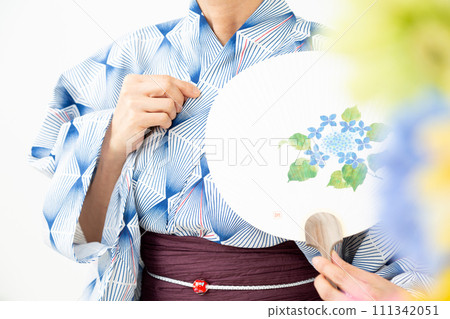 Middle-aged woman wearing a blue yukata and holding a fan 111342051