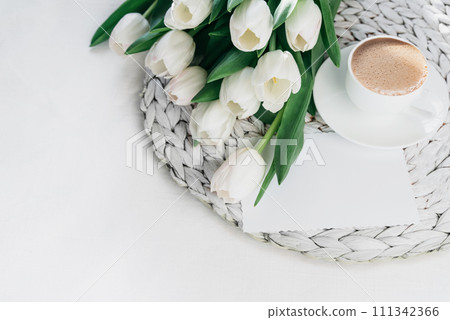 Cozy morning coffee cup with white tulip flowers from above, breakfast on Mothers day or Womens day. Top view with copy space Floral composition Romantic background 111342366