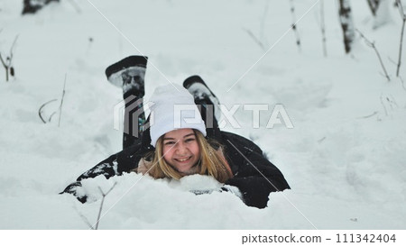 A girl falls on the snow in winter in the forest. 111342404
