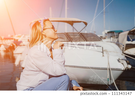 Woman in white shirt in marina , surrounded by several other boats. The marina is filled with boats of various sizes, creating a lively and picturesque atmosphere. 111343147