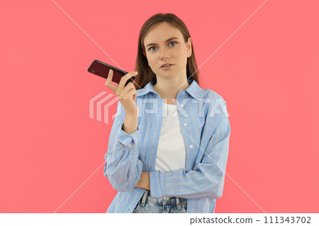 An attractive young girl holds a smartphone in her hands 111343702